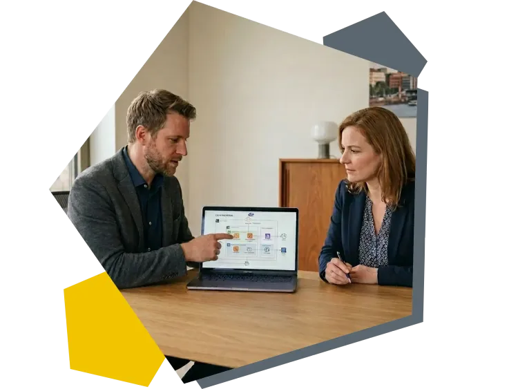 Zwei Fachpersonen sitzen an einem Tisch und besprechen auf einem Laptop die Struktur einer Anwendung im Rahmen von Application Management.