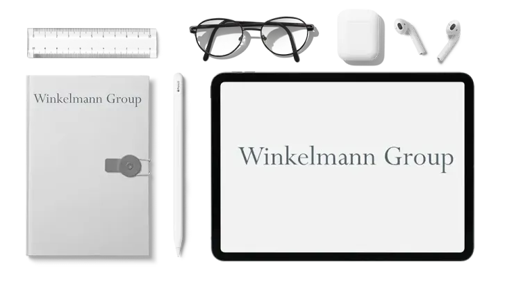 User-Helpdesk und Support für die Winkelmann Group Büroutensilien mit Winkelmann Group Logo liegen auf einer Schreibtischplatte